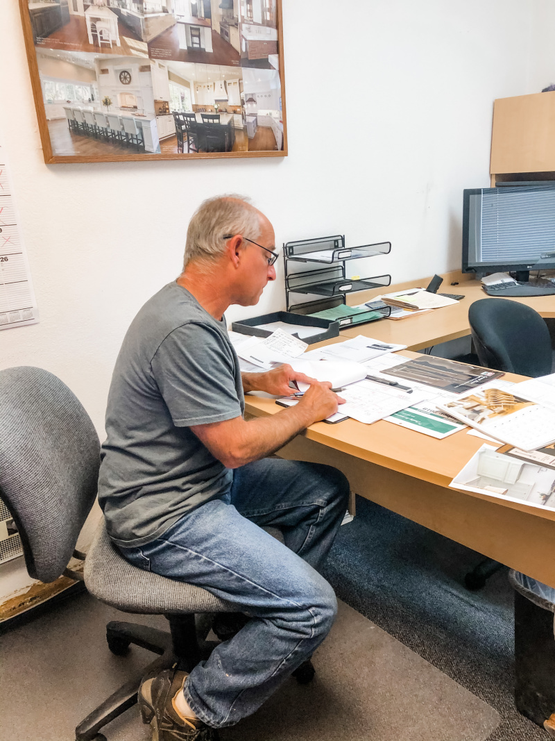 Cabinet maker sitting at desk with plans.