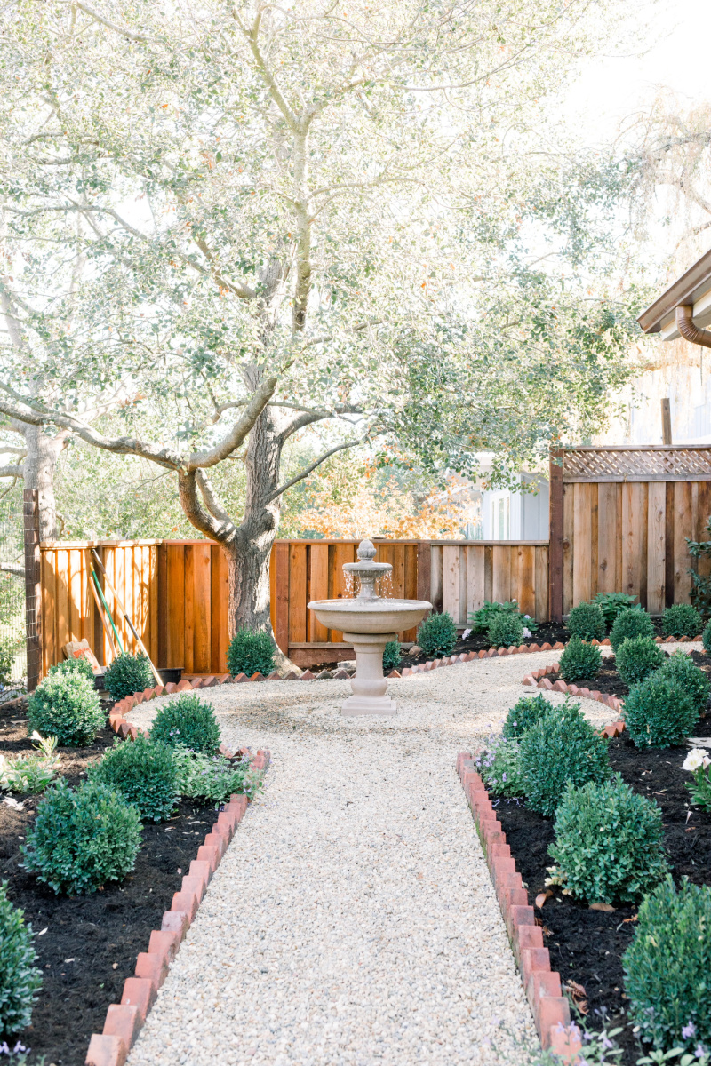 Garden gravel path lined with brick leading to fountain