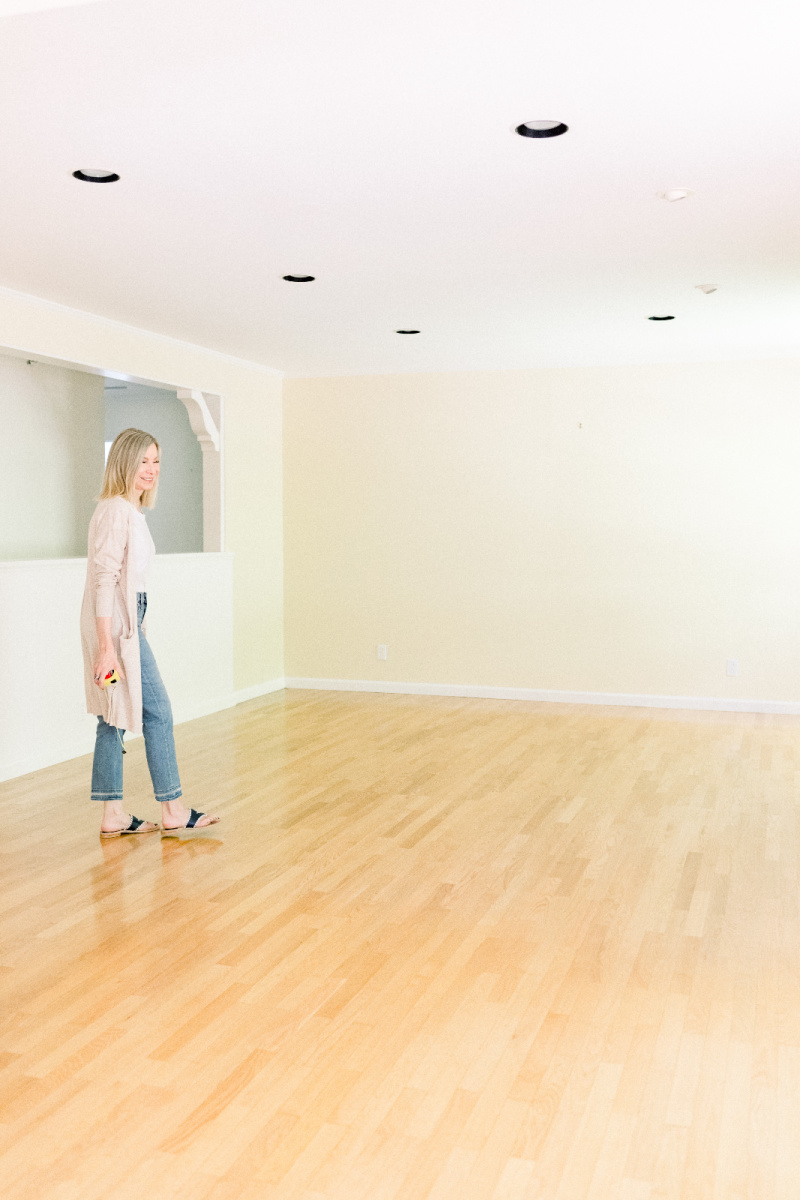 Woman standing in empty living room prior to renovation