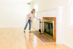 Woman looking at fireplace in empty room before renovation