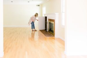 Woman looking into fireplace box in empty room before renovation