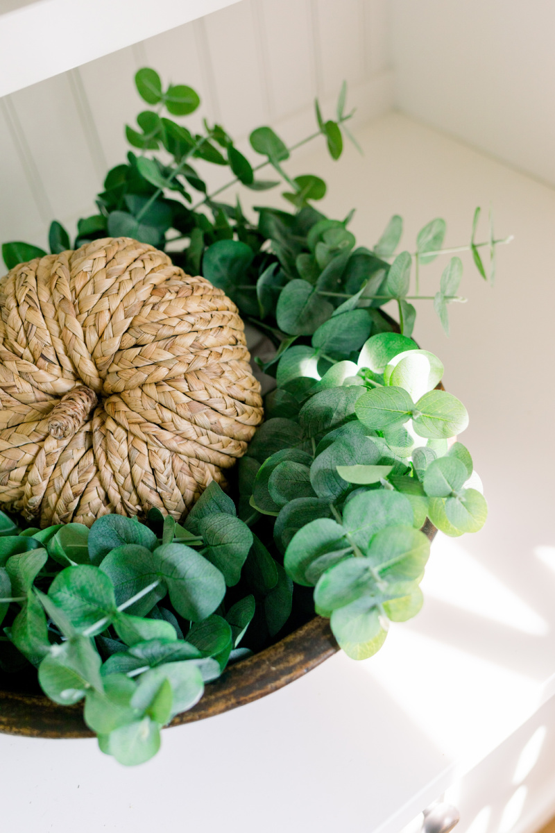 Eucalyptus leaves and woven pumpkin in wooden bowl