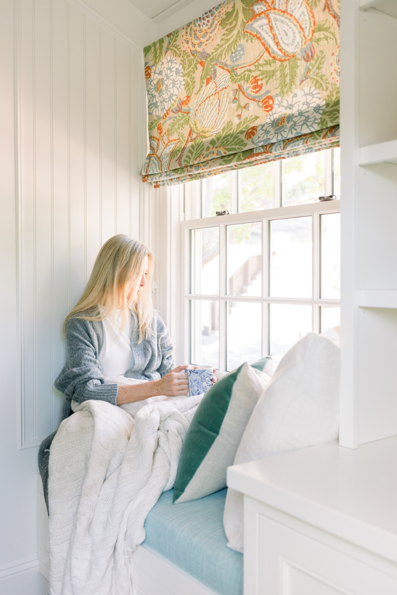 Woman sitting in window seat with mug