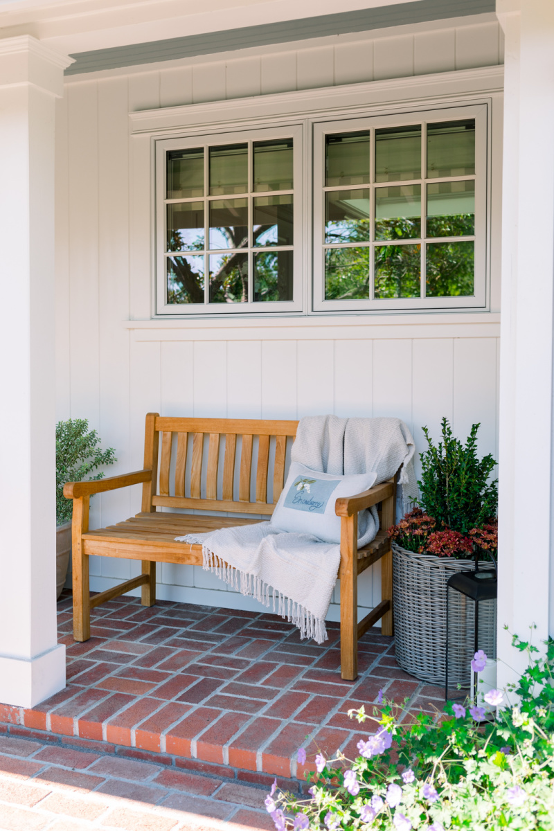 Teak bench on front porch decorated for fall