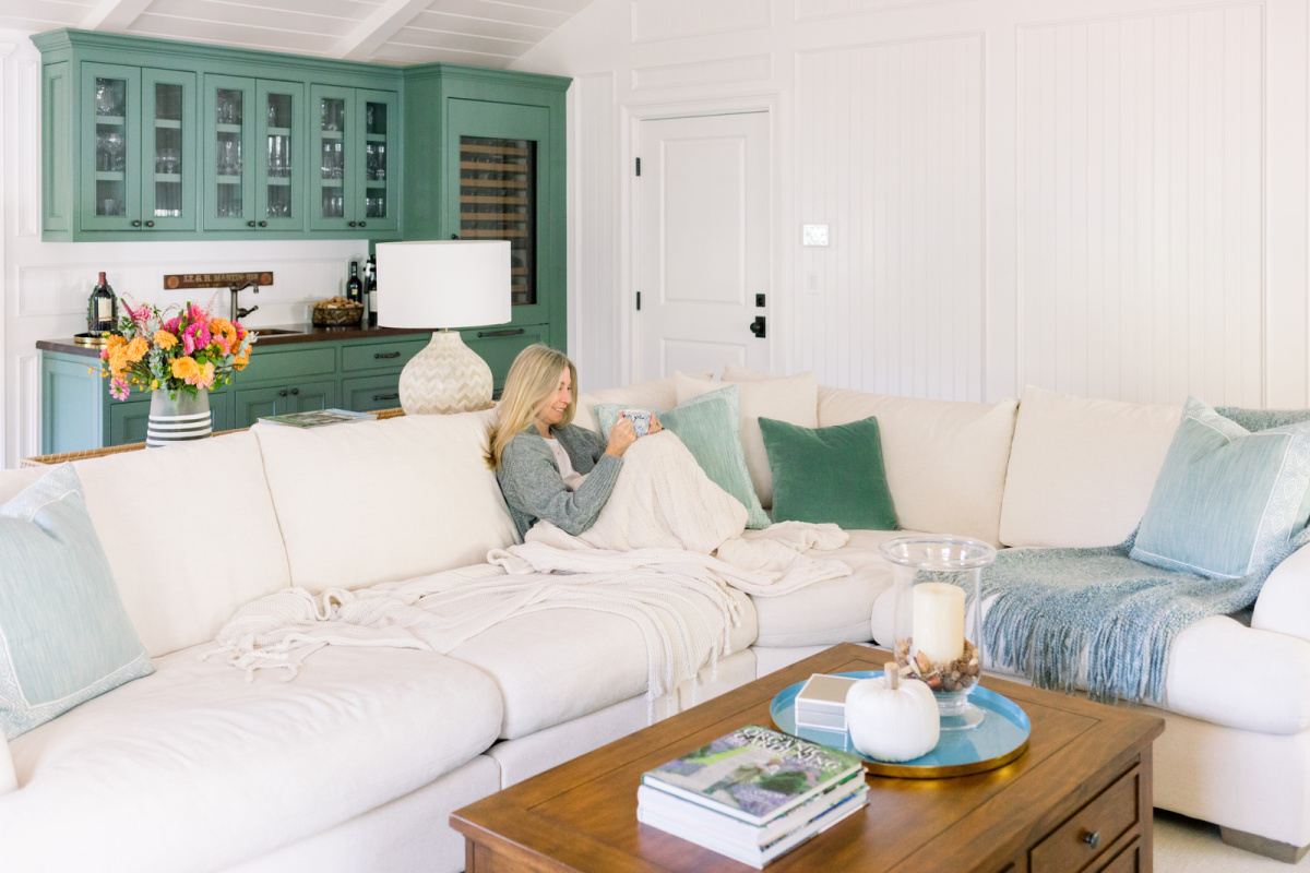 Woman with coffee mug on sofa under blanket