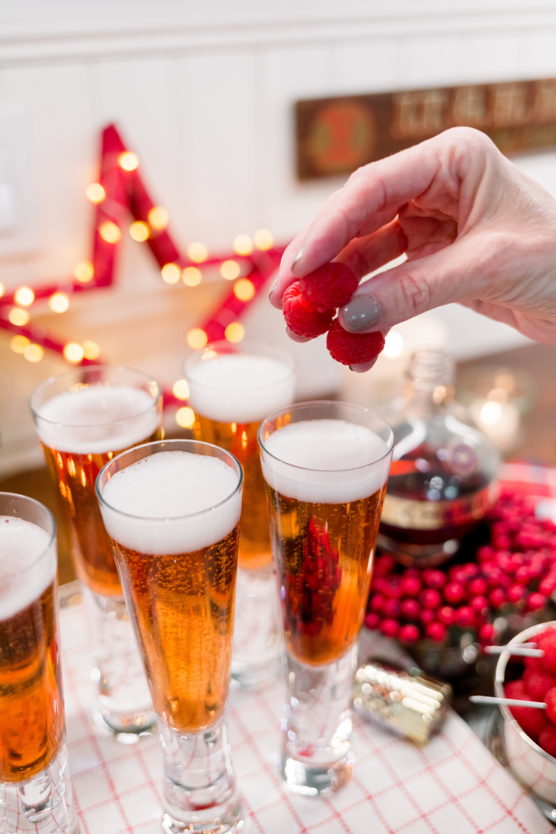Adding raspberry garnish to tray of champagne glasses