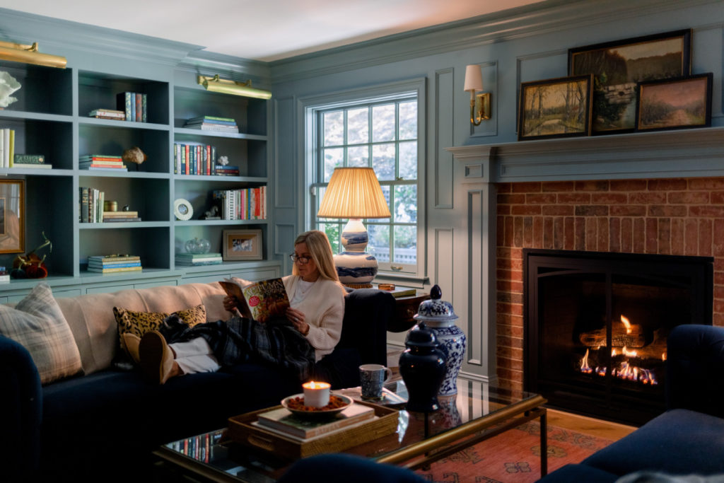 Woman reading on sofa by fire
