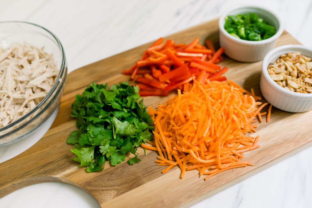 Bowl of shred chicken and board of cut vegetables