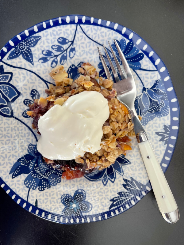 Blueberry crisp and whipped cream on blue and white plate
