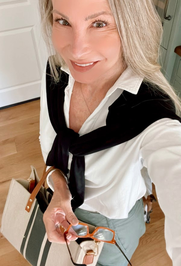 Woman taking selfie with fall sweater over shoulders.