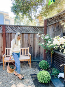 Woman standing in her garden in front of bench.