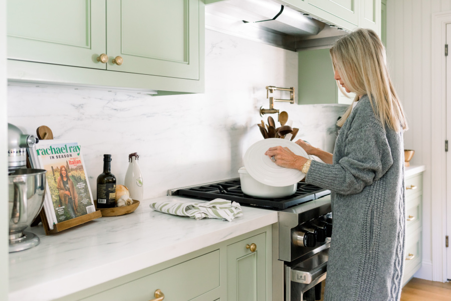 Woman stirring pot in green kitchen painted Farrow & Ball Vert de Terre