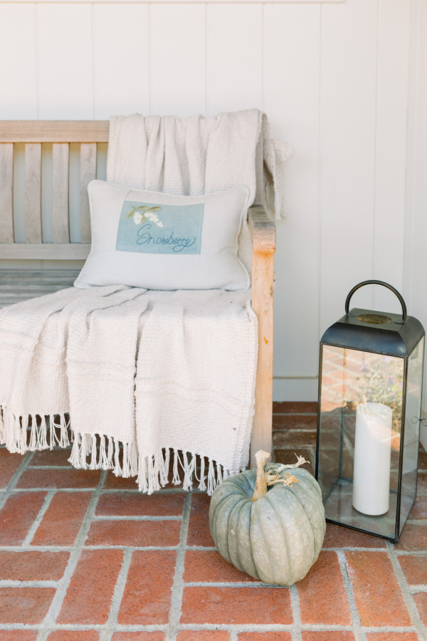 Front porch bench next to lantern and pumpkin.