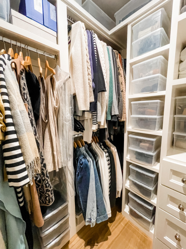 Walk in closet full of clothes and shoes.