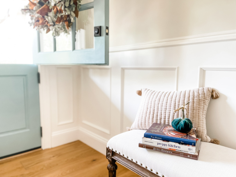 Books on an entry bench with pumpkin on top.