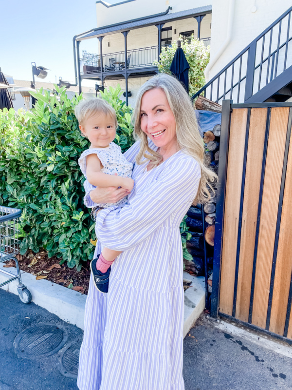 Woman holding baby outside restaurant.