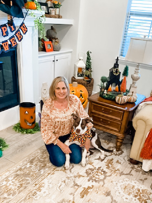 Woman and dog sitting on rug in Halloween decorated family room.