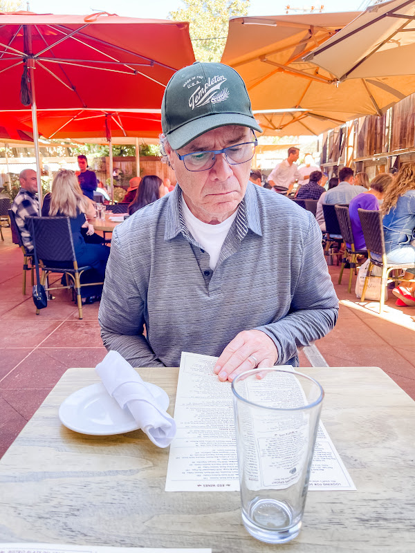 Man perusing menu on restaurant patio.