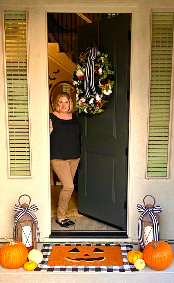 Woman standing in entryway decorated for Halloween.