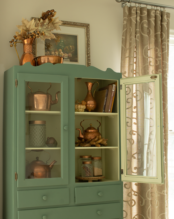 Erin Evolving green cupboard with copper pots.