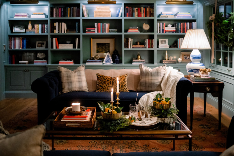 Home library room with blue velvet sofa and built in book shelves decorated for Christmas.
