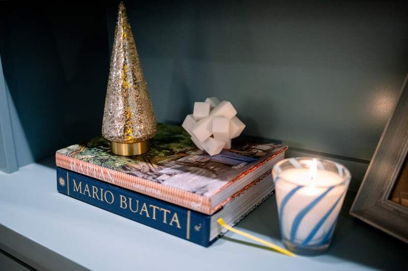 Gold glitter tree and blue and white Nest candle on a book shelf.