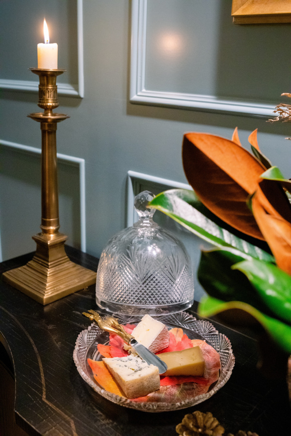 Domed cheese plate on sideboard next to brass candlestick.