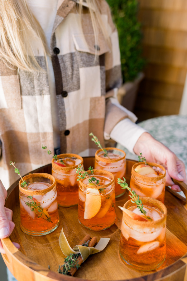 Woman carrying tray of Apple Cider Aperol Spritz.