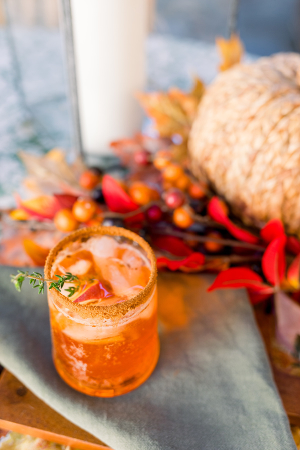 Apple Cider Aperol Spritz on green napkin next to woven pumpkin.