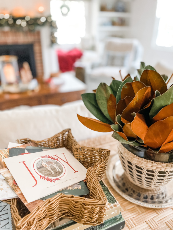 Christmas cards next to bowl of magnolia leaves.