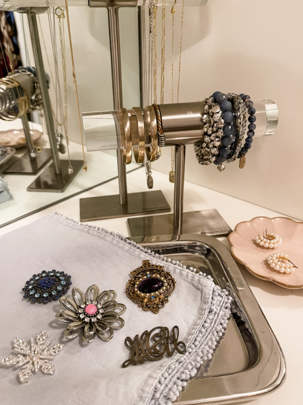 Tray of pins on dresser with other jewelry.