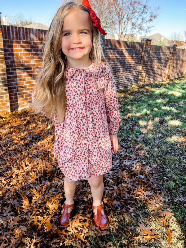 Little girl in dress standing in playground.