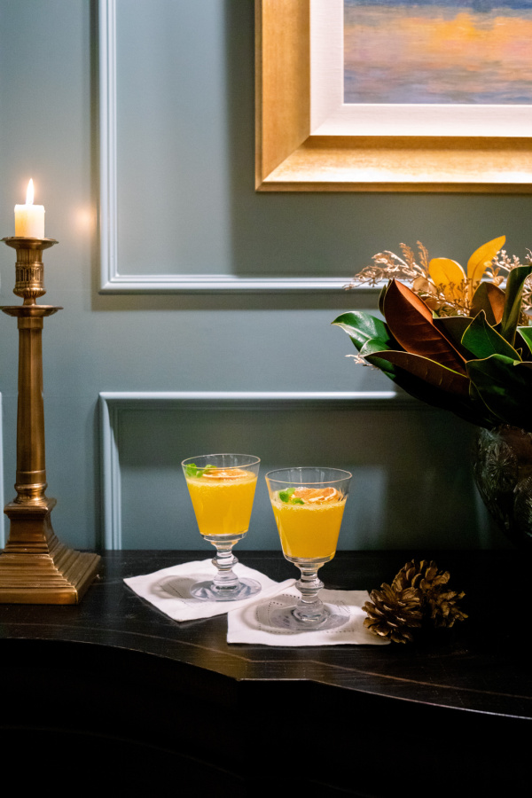 Glasses of Cara Cara Winter Spritz on buffet next to candle.