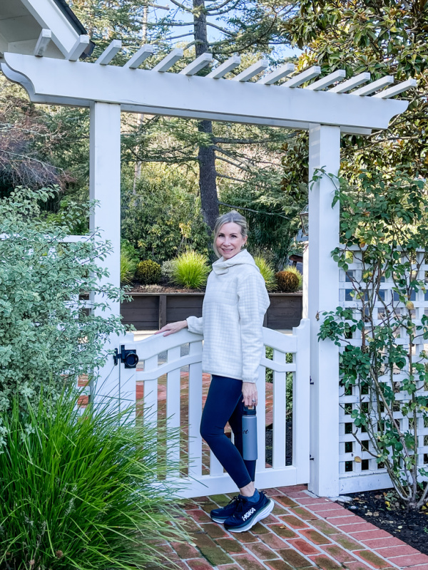 Woman standing under pergola dressed for a workout.