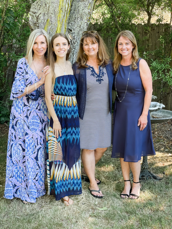 Four women standing together in backyard.