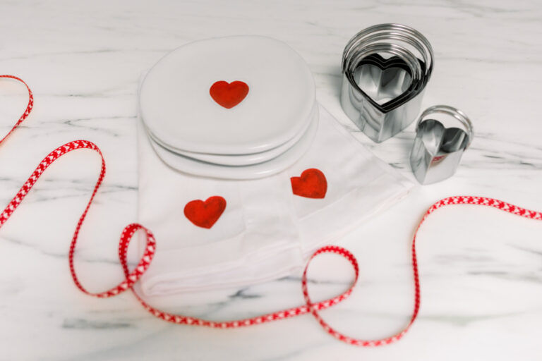 Valentine plates, ribbon and cookie cutters on counter.