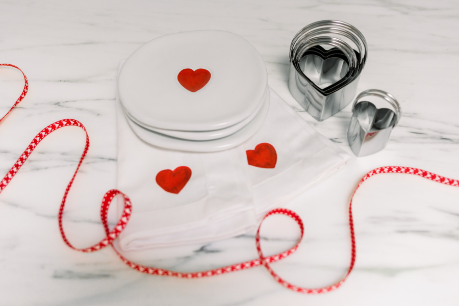 Valentine plates, ribbon and cookie cutters on counter. 