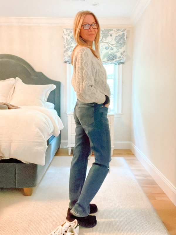 Woman wearing jeans and grey cardigan.