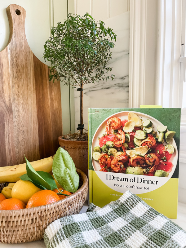 Cookbook next to rattan bowl of fruit.