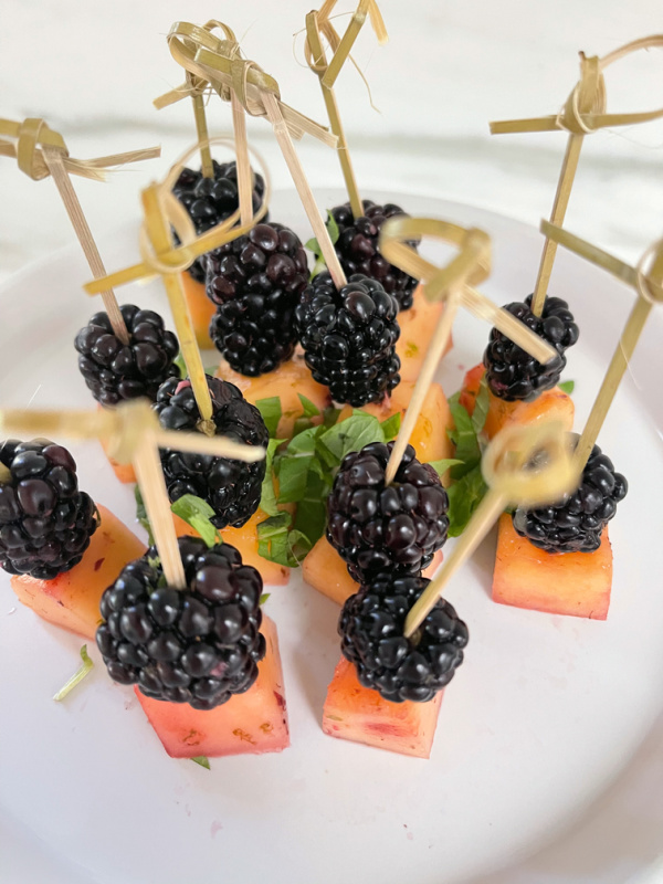 Cantaloupe and blackberries on cocktail picks.