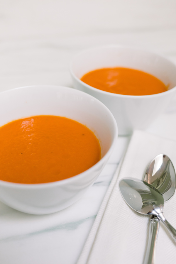 Tomato soup in bowls with spoons on side.