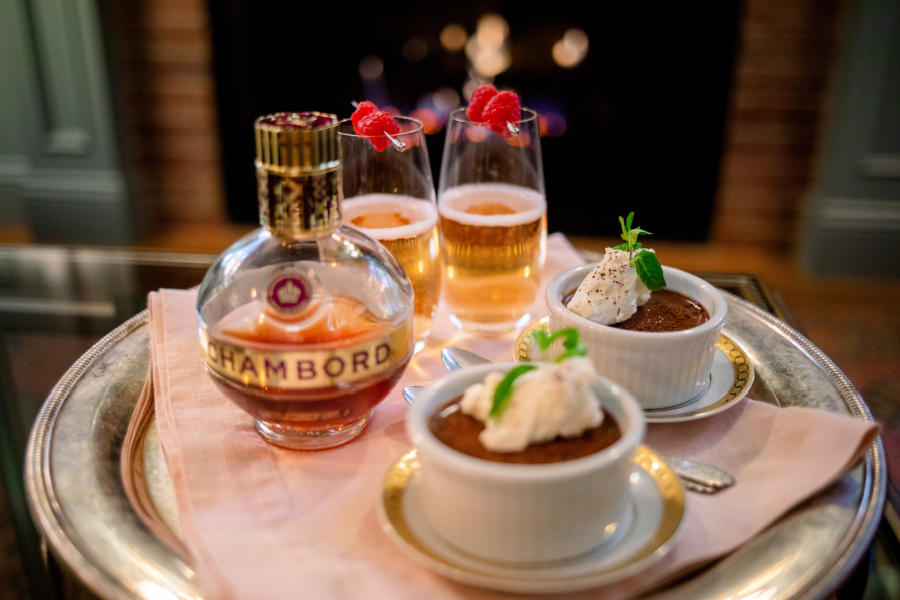 Raspberry Kir Royales on a tray with chocolate pot de cremes in front of the fire.