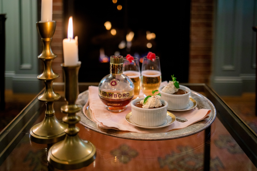 Raspberry Kir Royales on a tray with chocolate pot de cremes in front of the fire.