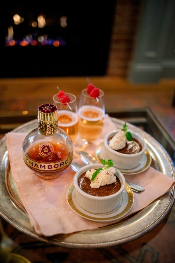 Raspberry Kir Royales on a tray with chocolate pot de cremes in front of the fire.