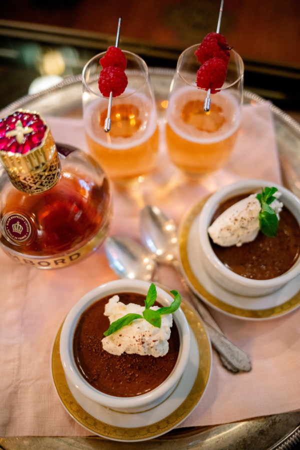 Raspberry Kir Royales on a tray with chocolate pot de cremes in front of the fire.