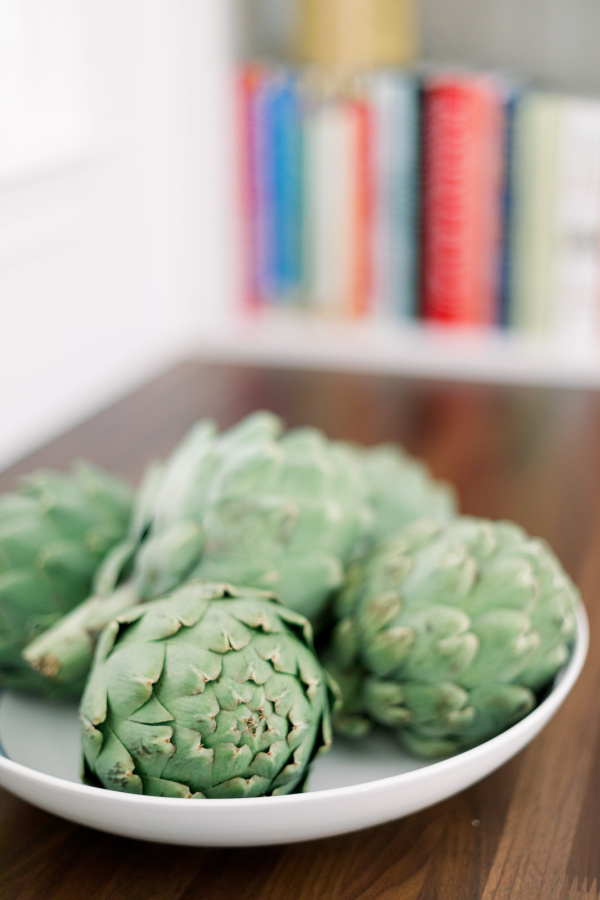 Artichokes in bowl on kitchen counter.