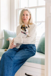 Woman sitting in window seat holding Jack Russell Terrier.
