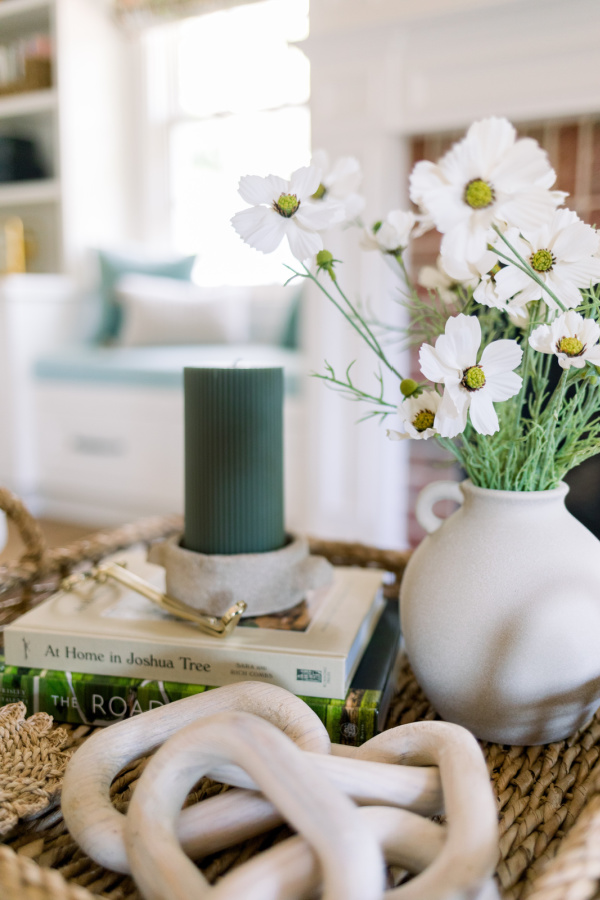 Coffee table vignette with green candle and sand colored flower vase.