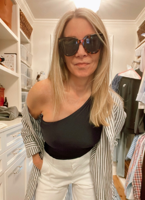 woman wearing bathing suit, shorts and striped blouse.