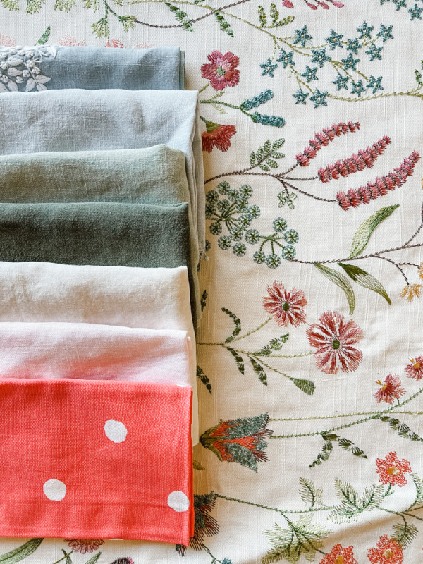 Floral table throw with colorful napkins on top.